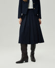 Deep Navy pleated midi skirt on model, lower-body front view highlighting the pressed pleats and midi length
