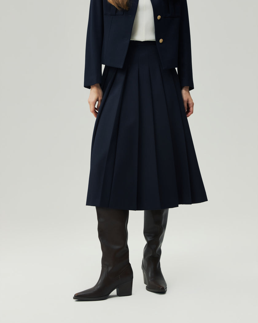 Deep Navy pleated midi skirt on model, lower-body front view highlighting the pressed pleats and midi length