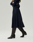 Midi Skirt in Deep Navy on model, walking side view showing the fluid pleated hem