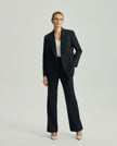 Model wearing Ecole charcoal grey tailored trousers with a matching blazer