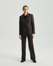 Model wearing Ecole high-rise trousers in ebony with a matching blazer