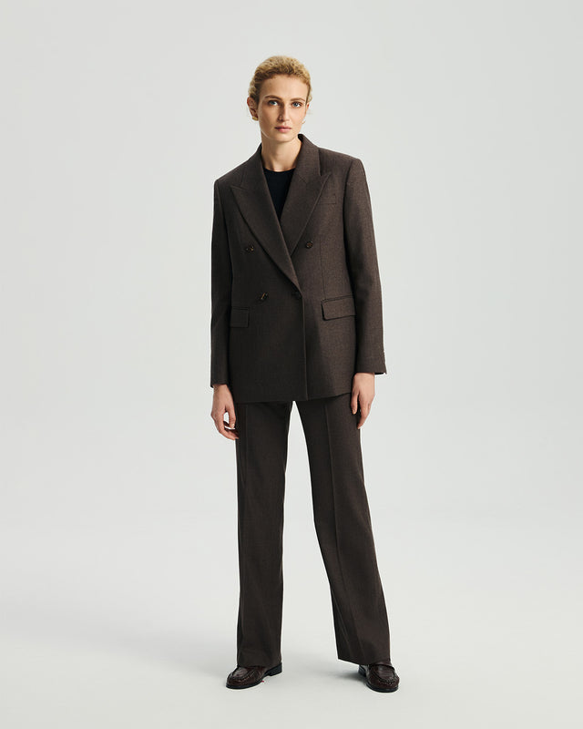 Model wearing Ecole high-rise trousers in ebony with a matching blazer