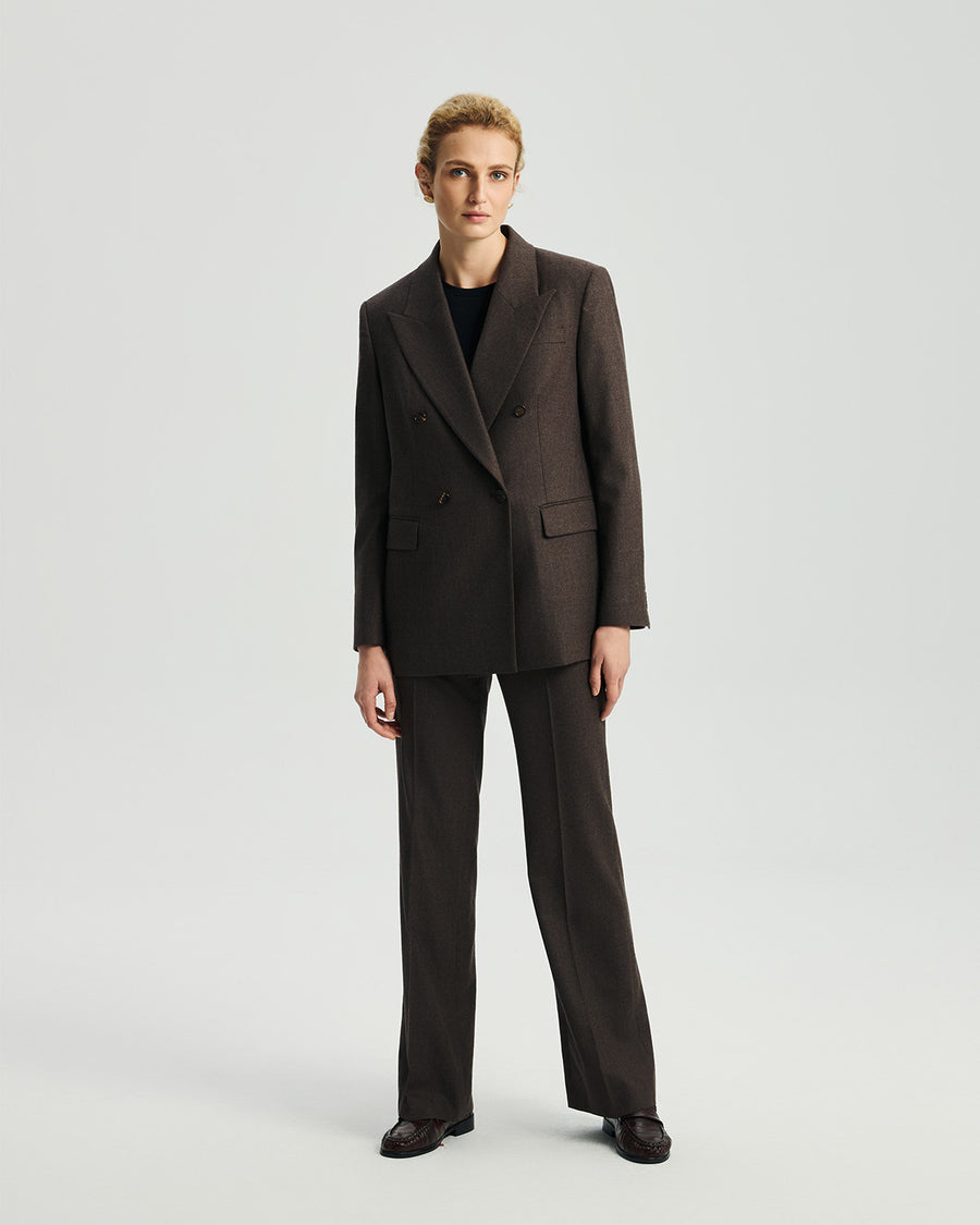 Model wearing Ecole high-rise trousers in ebony with a matching blazer