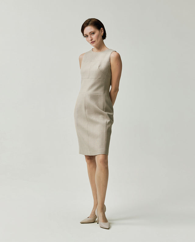 Model wearing the Curie sleeveless dress in textured apricot with a fitted waist and straight silhouette
